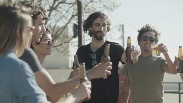 Alegre amigos tintineo botellas de cerveza durante la fiesta al aire libre — Vídeo de stock