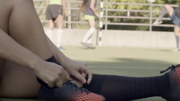 Vista lateral del jugador de fútbol femenino atando zapatos en el estadio — Vídeos de Stock