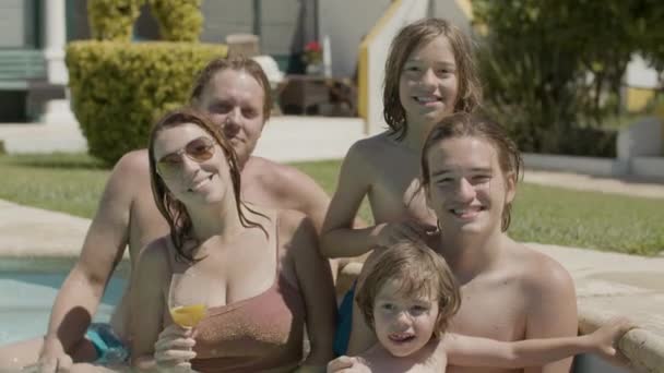Keluarga bahagia berdiri di kolam renang dan mengangkat tangan — Stok Video