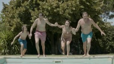 Beyaz bir aile el ele tutuşmuş ve yüzme havuzuna dalmış.