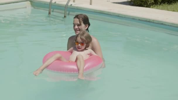 Menino feliz sentado no tubo inflável na piscina — Vídeo de Stock