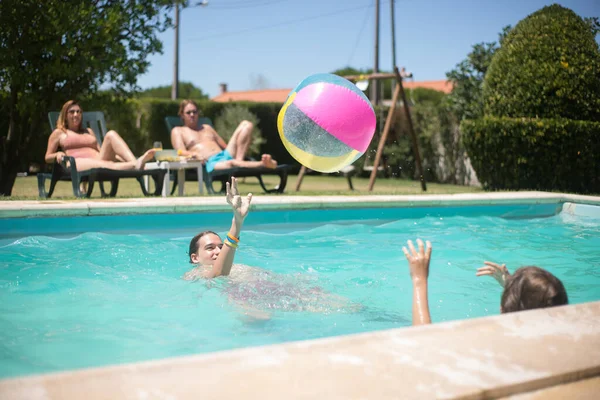 Yüzme havuzunda top oynayan keyifli kardeşler — Stok fotoğraf