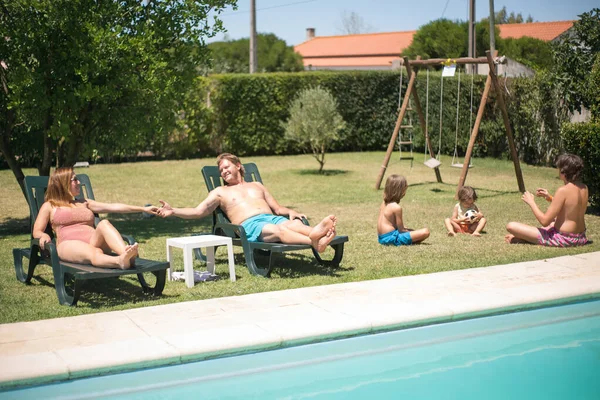 Mutlu ebeveynler yüzme havuzunun yanında güneşleniyor.