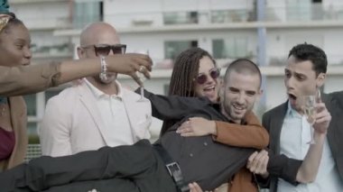 İş arkadaşları yöneticilerini ellerinde tutuyor ve zaferi kutluyorlar.