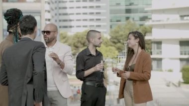 Çalışanlar köpüklü şarap içip iş partisinde konuşuyorlar.