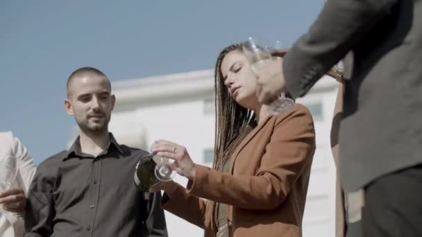 Glad kvinna häller champagne i glas på affärsfest — Stockvideo