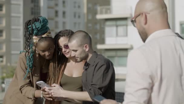 Colegas felizes olhando para a tela do telefone durante a festa ao ar livre — Vídeo de Stock