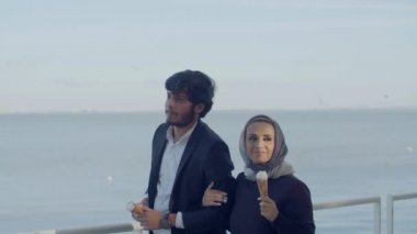 Arap erkek ve kadın sette yürüyüp dondurma yiyorlar.
