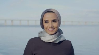 Mavi gökyüzünün arkasında duran gülümseyen Arap kadın