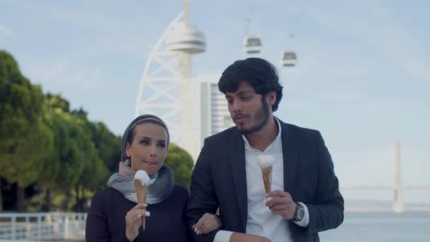 Αραβικό ζευγάρι περπάτημα χέρι στο χέρι εξωτερική και τρώει παγωτό — Αρχείο Βίντεο