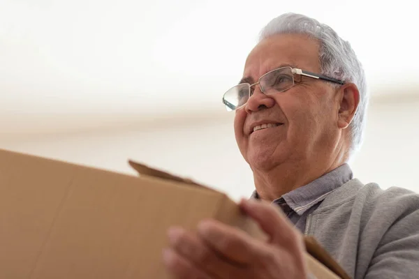 Happy elderly man carrying box in new house