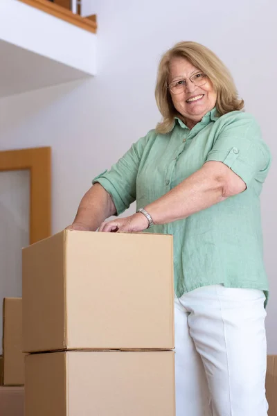 Elderly woman unpacking things in new house