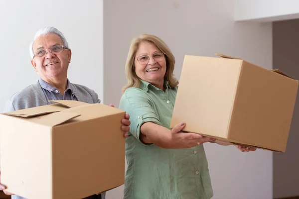 Glada äldre par flyttar in i nytt hus Stockbild