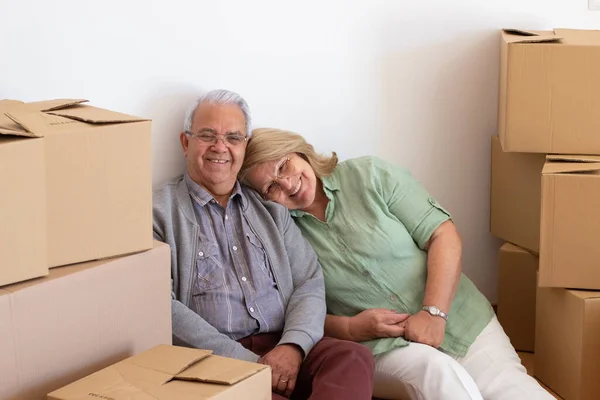 新しい家に引っ越している間にリラックスしている幸せな高齢者のカップル ストックフォト