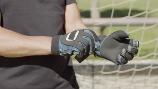 Зрілий воротар носить рукавички, стоячи на стадіоні — стокове відео
