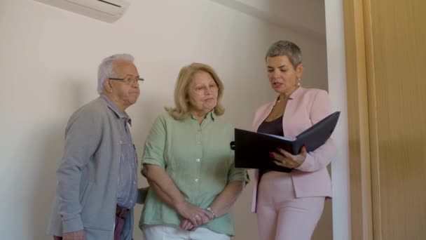 Realtor mostrando documentos imobiliários casal sênior em casa — Vídeo de Stock