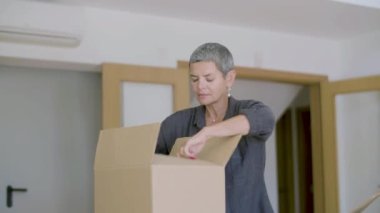 Yeni eve taşındıktan sonra kutuları açan neşeli kadın.