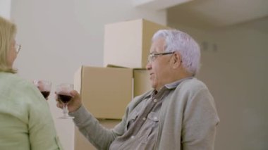 Yeni eve taşındıktan sonra yaşlı çift yerde şarap içiyor.