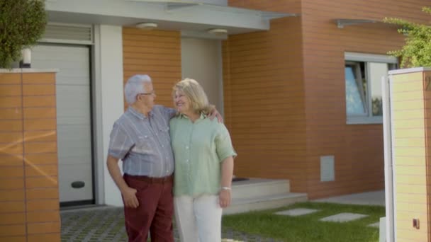 Spännande äldre par står bredvid nytt hus och kramas — Stockvideo