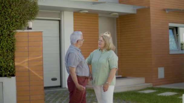 Coppia anziana in piedi all'aperto e discutere l'acquisto di nuova casa — Video Stock