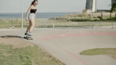 Odaklanmış kız yaz günü kaykay parkında uzun kaykay sürüyor.