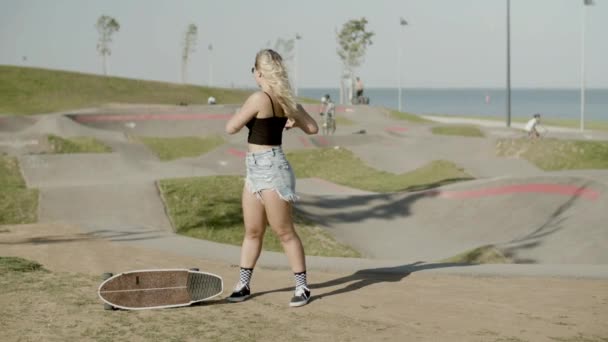 Весела дівчина зігрівається перед тренуванням у скейт-парку — стокове відео