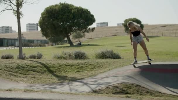 Skupiona dziewczyna ujeżdżająca longboard w skate parku w letni dzień — Wideo stockowe