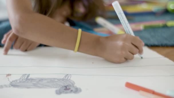 女の子は床に横たわって紙の上にフェルトペンで線を描く — ストック動画
