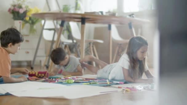 Gyerekek feküdt a padlón, és rajzol képeket színes ceruzák — Stock videók