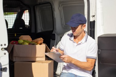 Yetişkin teslimatçı teslimattan önce belgeleri kontrol ediyor.
