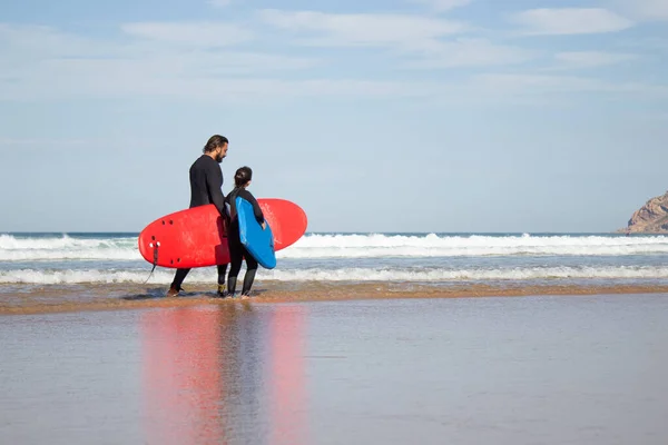 Baba ve kızı bulutlu sahilde spor yapıyor.