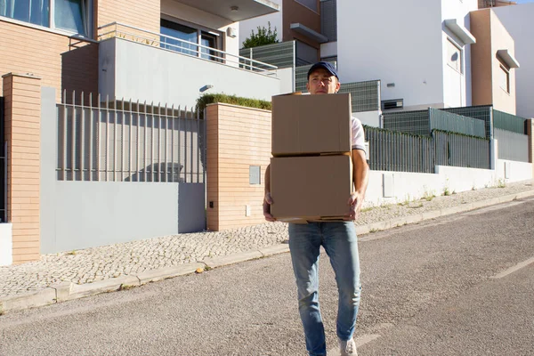 Yetişkin bir teslimatçı bir yığın kutu taşıyor.