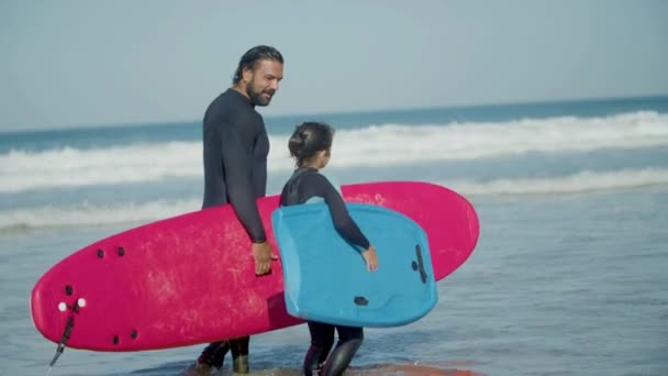 Тренер по серфингу с ограниченными возможностями прогулка вдоль побережья с девушкой — стоковое видео