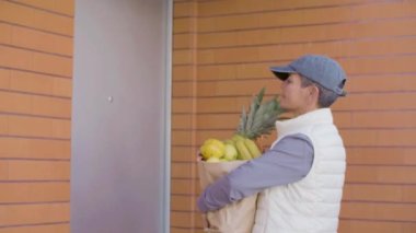 Meyve dolu çantalı kadın kurye müşterinin kapısını çalıyor.