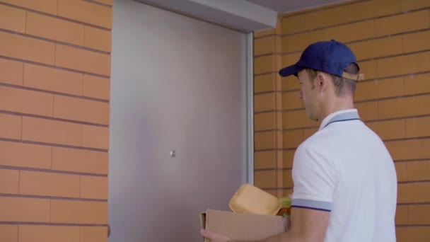 Caucasian courier giving cardboard box with groceries to woman — Stock Video