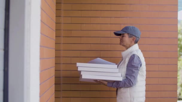 Ženský kurýr v uniformě doručující pizzu muži u něj doma — Stock video