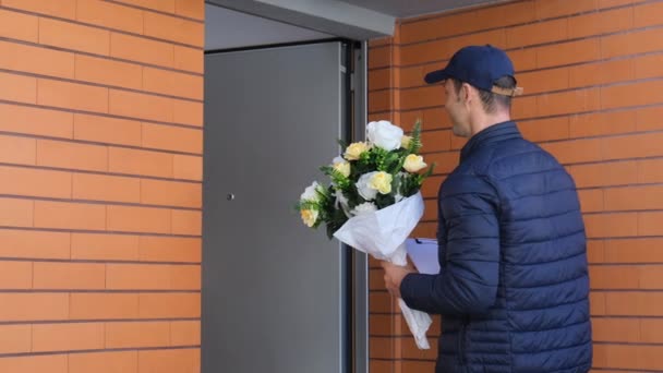 Жінка відкриває вхідні двері і отримує квіти від кур'єра — стокове відео