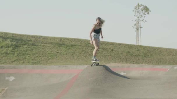 夏の日にスケートパークでロングボードに乗るフォーカス女の子 — ストック動画