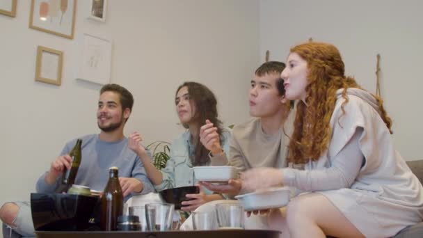 Amigos Sentados Sofá Viendo Televisión Hablando Comiendo Patatas Fritas Emocionados — Vídeo de stock