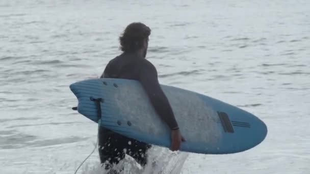 Homem com perna artificial em terno de mergulho surfando no oceano — Vídeo de Stock