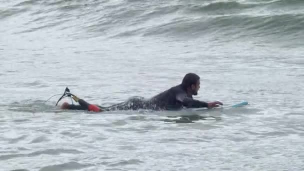 障害のあるスポーツマンが海のサーフボードで漕ぐ — ストック動画