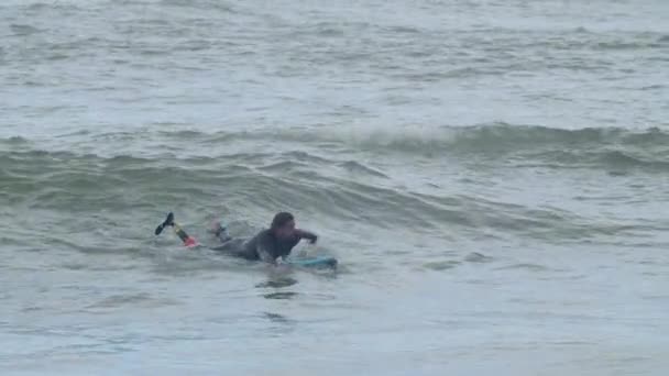 Uomo focalizzato con gamba artificiale cavalcare onda in oceano — Video Stock
