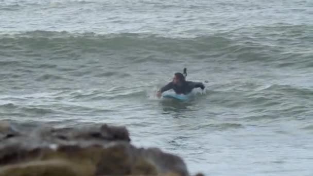 Hombre en traje de neopreno con discapacidad surfeando en el océano — Vídeos de Stock