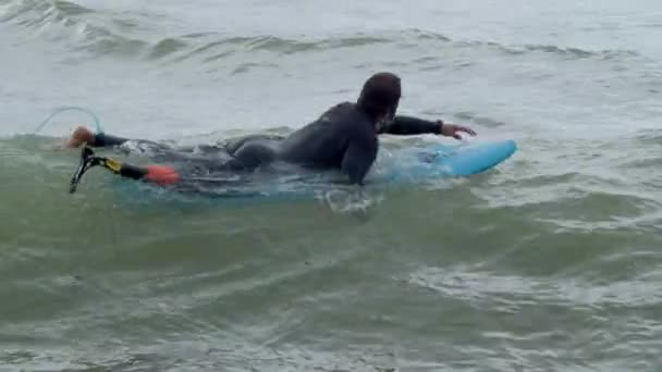 Atleta con gamba artificiale remare su tavola da surf in mare — Video Stock