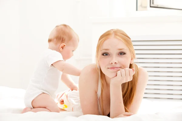Mother lies on carpet with baby — Stock Photo, Image