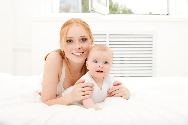 Moeder ligt op tapijt met baby — Stockfoto