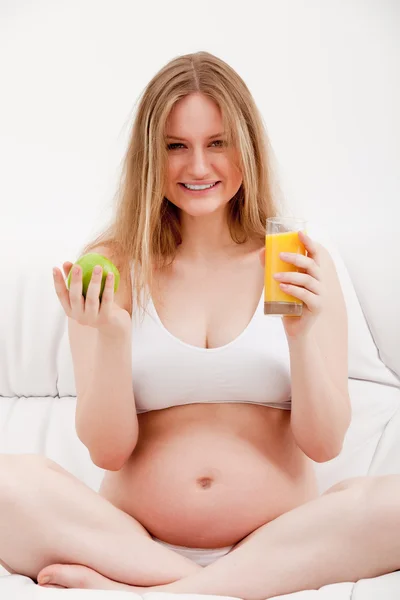 Mujer embarazada sosteniendo una manzana y jugo — Foto de Stock