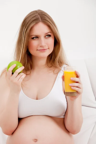 Mulher grávida segurando uma maçã e suco — Fotografia de Stock