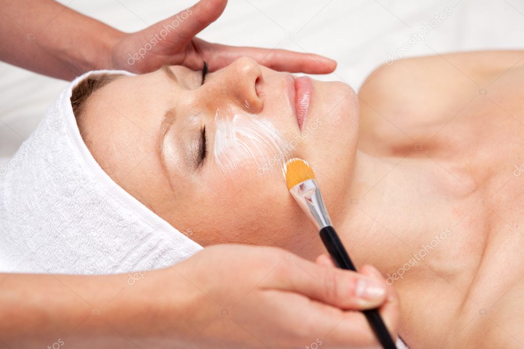 Spa therapy for woman receiving facial mask at beauty salon
