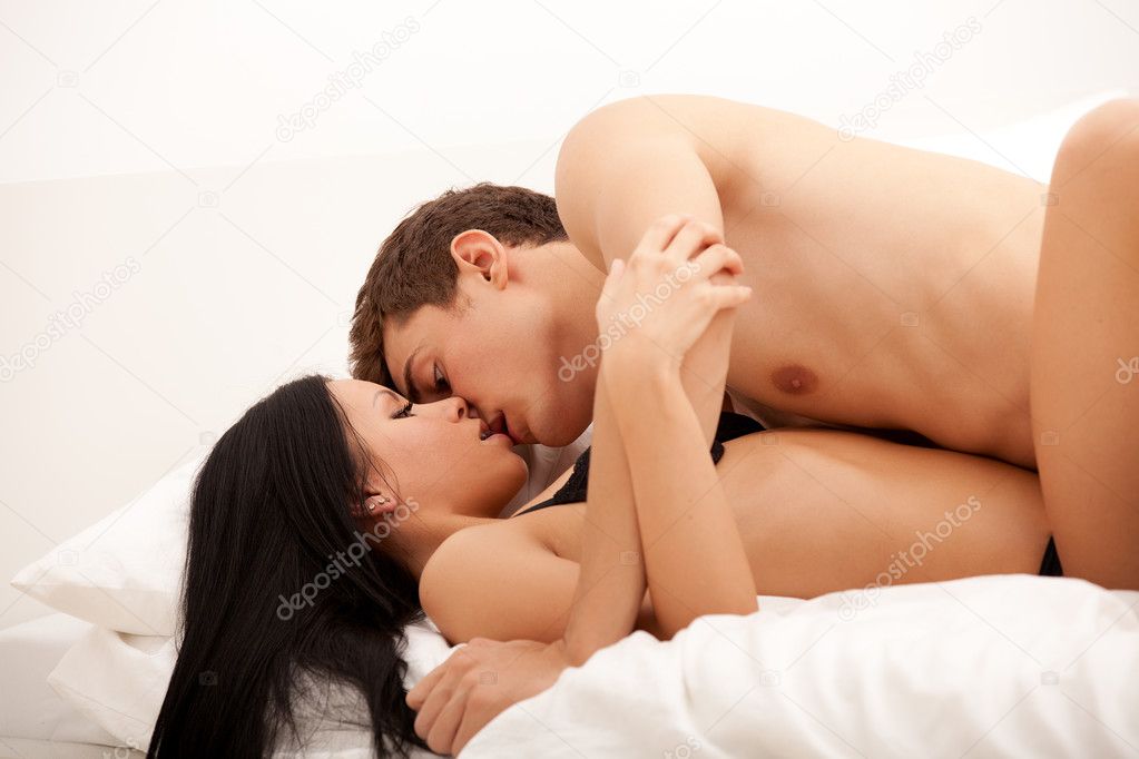 Sexy young couple kissing and playing in bed.
